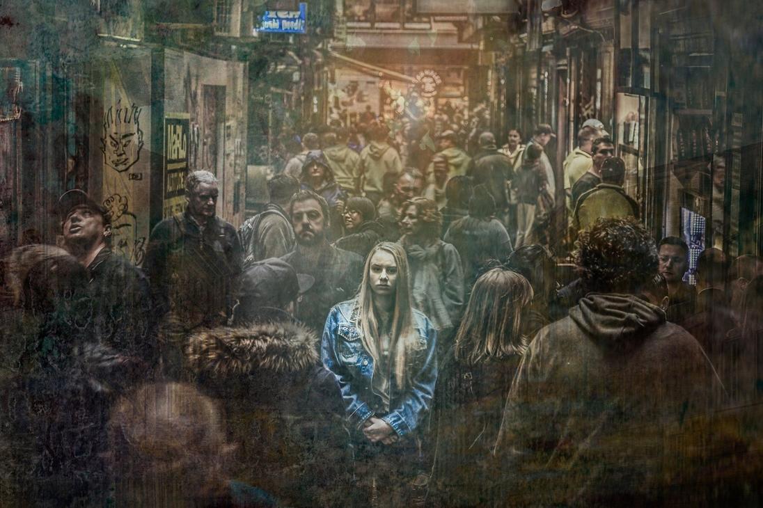girl in denim jacket standing in a crowd but feeling alone