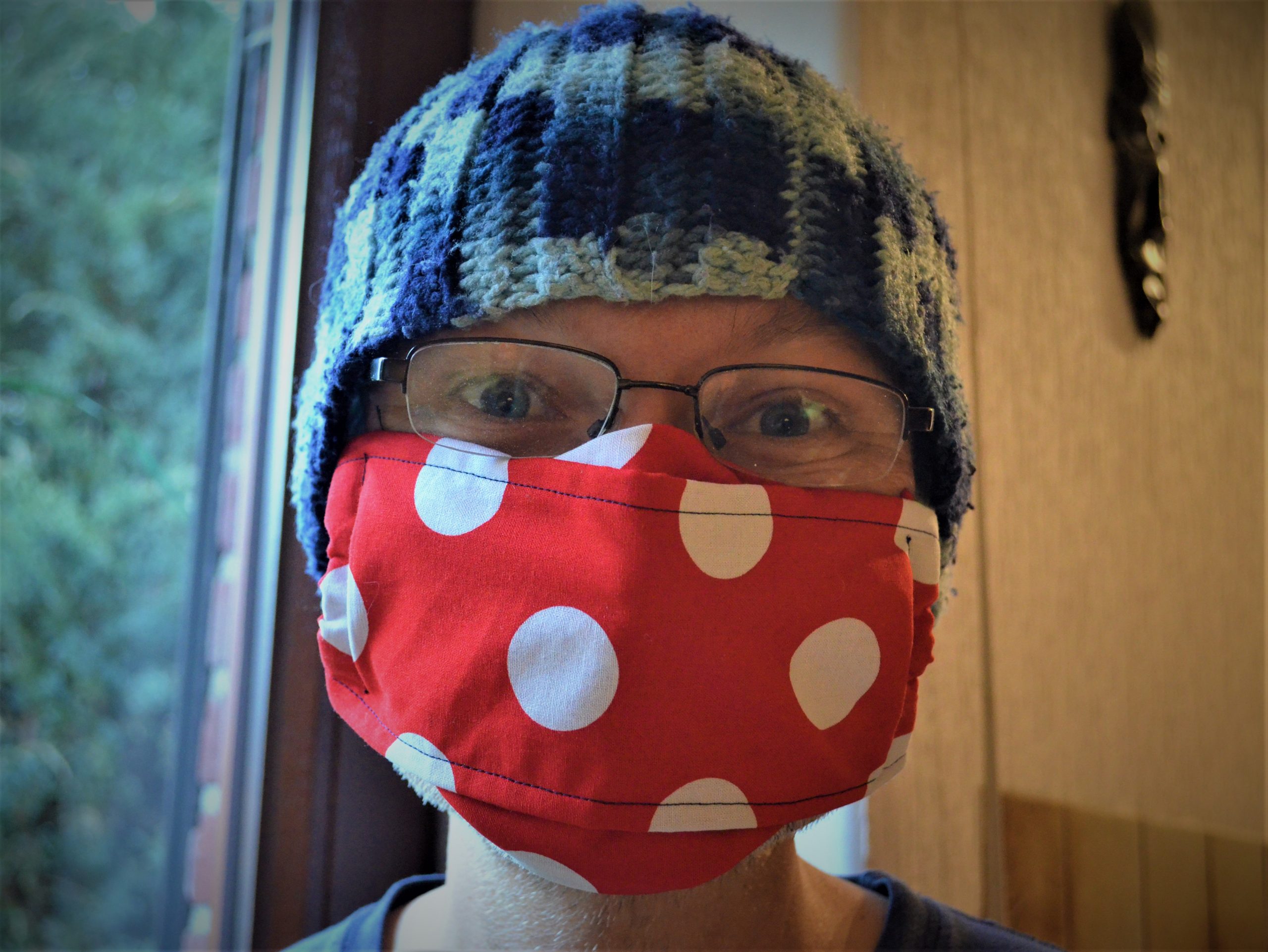 Person wearing large red face mask with white polka dots