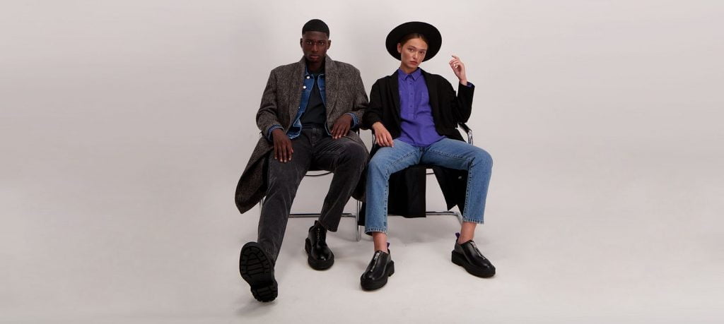 man and woman sitting in chairs on a neutral background by Amendi, a sustainable clothing brand