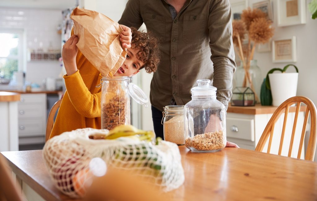 Father Helping Son To Refill Food Containers At Home Using Zero Waste Packaging