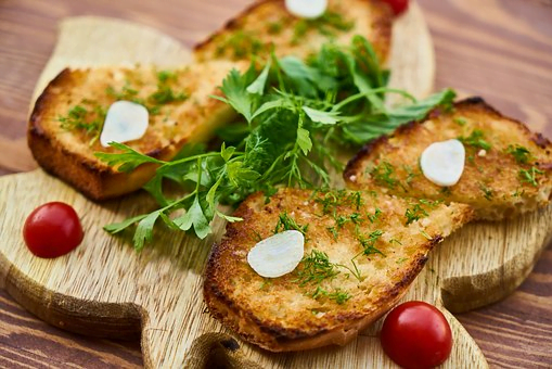 garlic bread on board with hearbs and tomatoes