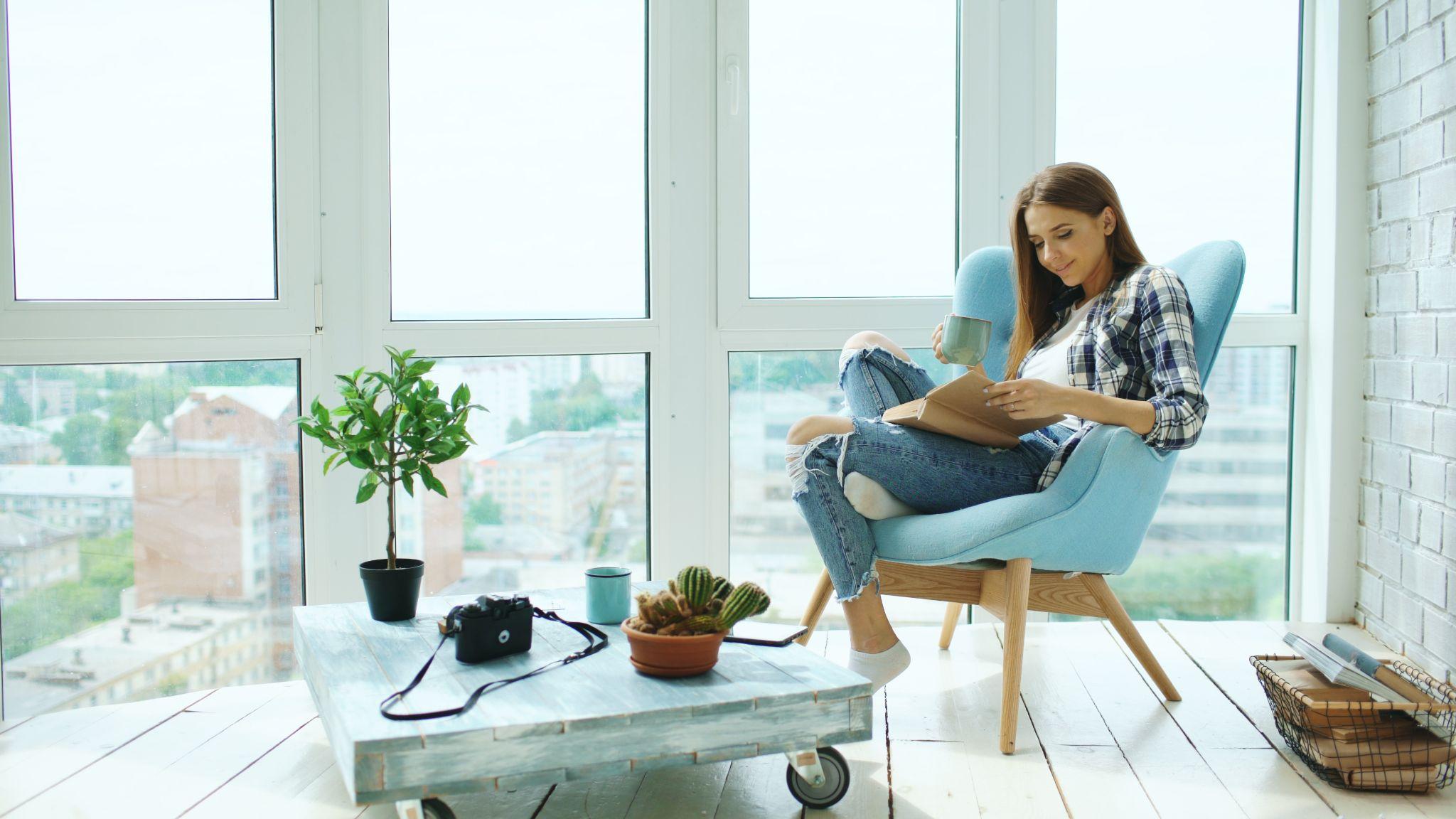 Sustainable Living Tips for an Earth-Friendly Home: woman reading book in comfortable chair with a view