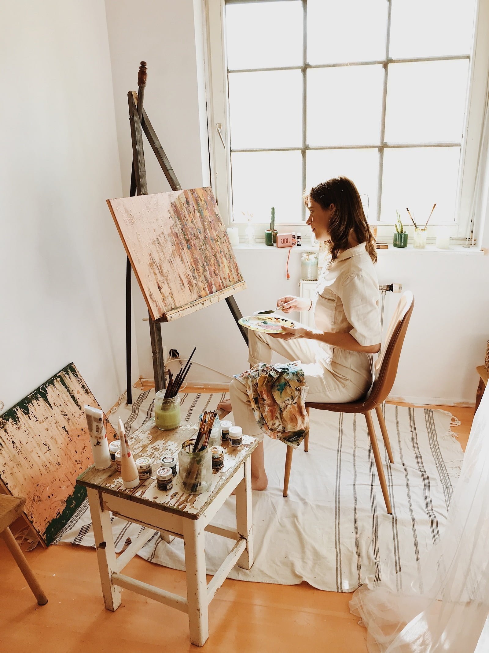 Sustainability in the Art World: Female painter wearing white at work in her studio