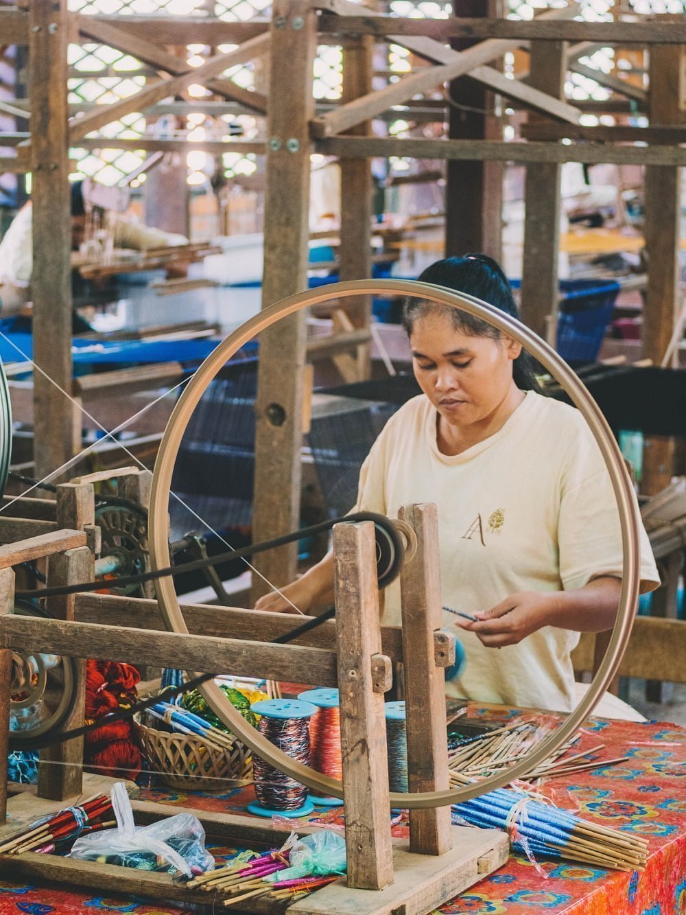 The Benefits of Sustainable Fashion: woman using spinning wheel with colorful thread