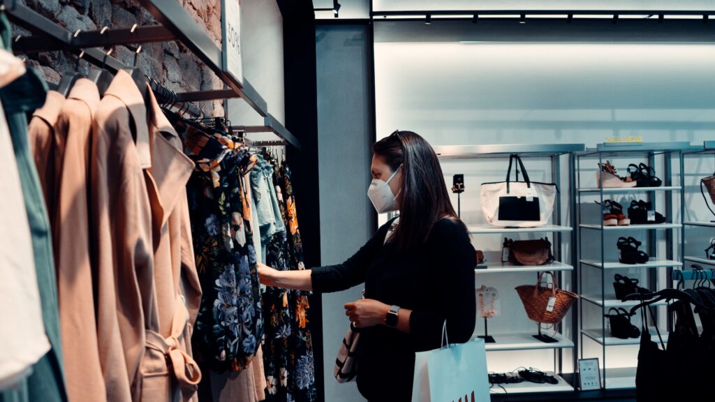 How to Shop More Sustainably: woman in mask shopping for clothes