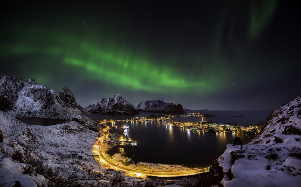 A man looking at the northern lights over Reine, Lofoten islands, Norway