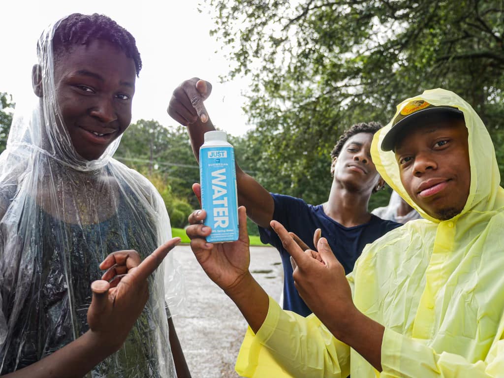 three boys pointing at a water bottle