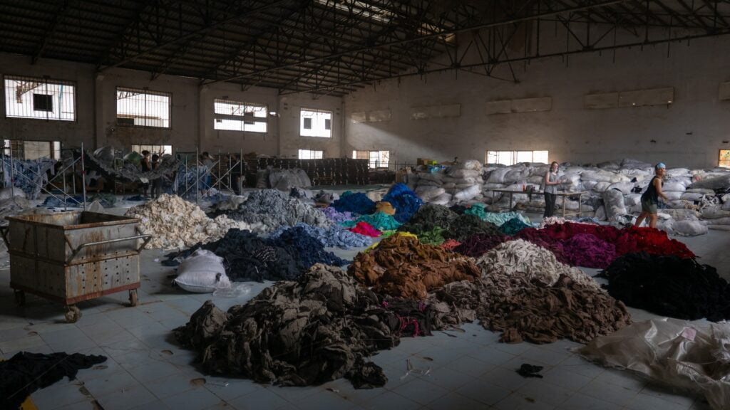 Why and How to stop fast fashion: Sorting through hundreds of tons of clothing in an abandoned factory for a social mission called Clothing the Loop.