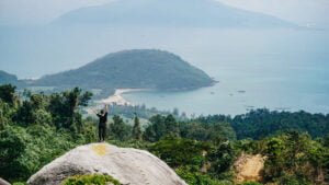 Your Guide to Sustainable Travel in Vietnam: woman with hands raised standing on boulder