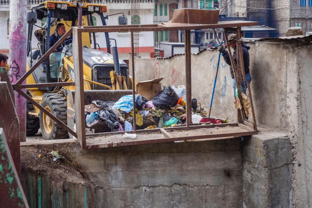 Waste and Landfills: A front loader pushing trash in a concrete passageway