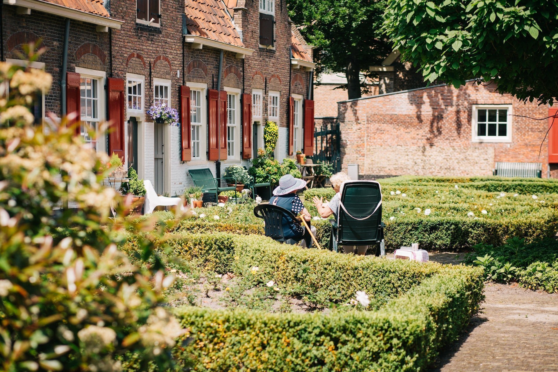 Sustainable and Accessible Home Updates in Your Golden Years: Elderly couple outside in a green garden by a brick home