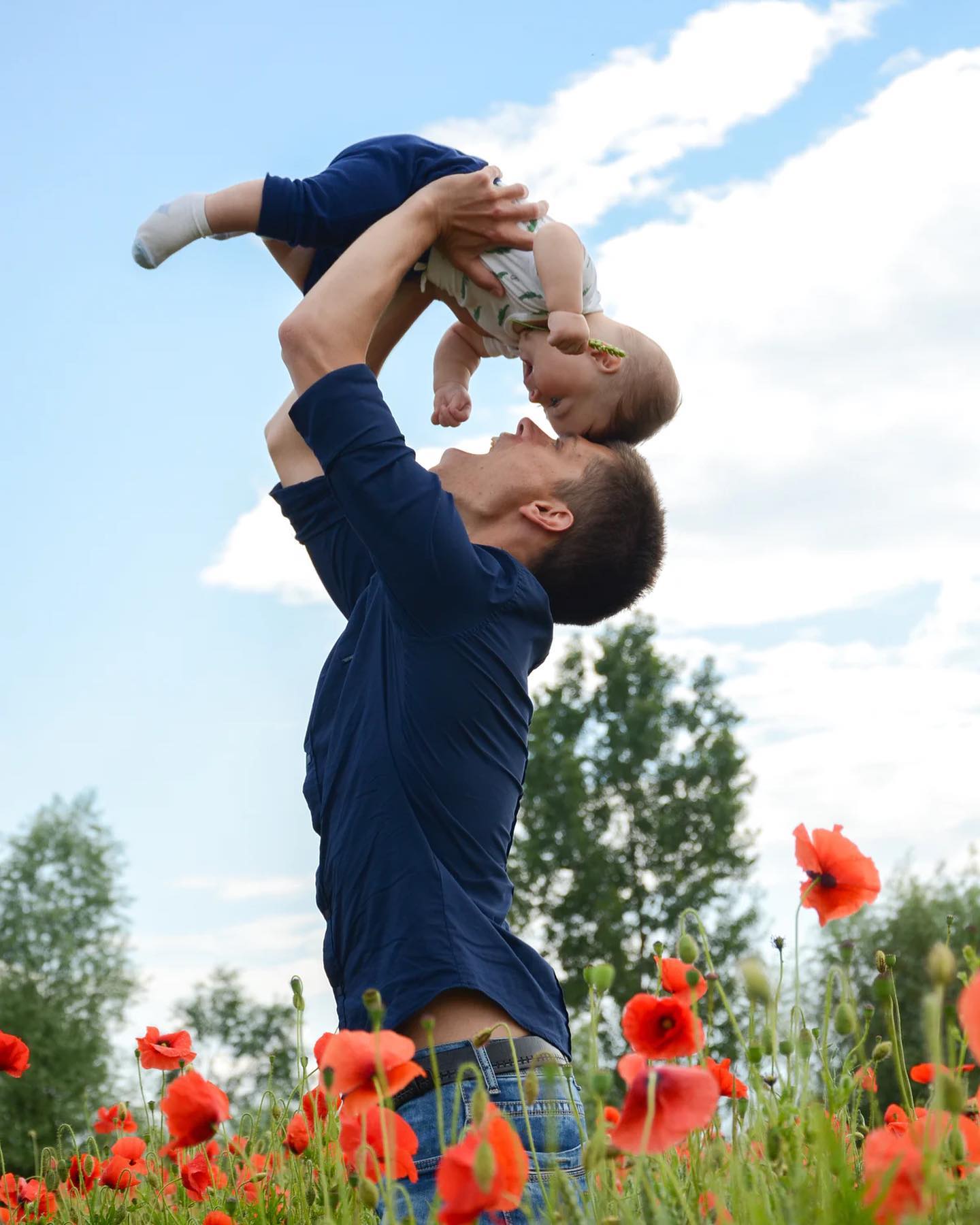 The New Age of Meaningful Gift Giving: Father holding child up, their heads touching, over a poppy field