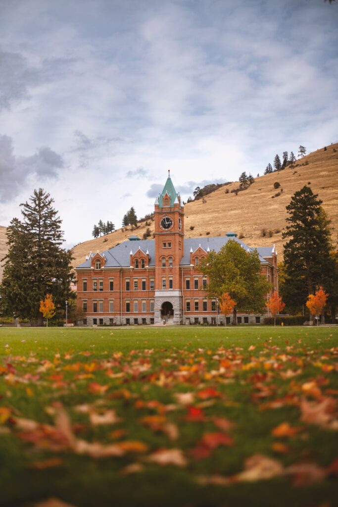 University Societies: Montana Universitym green field, grey sky, hills behind