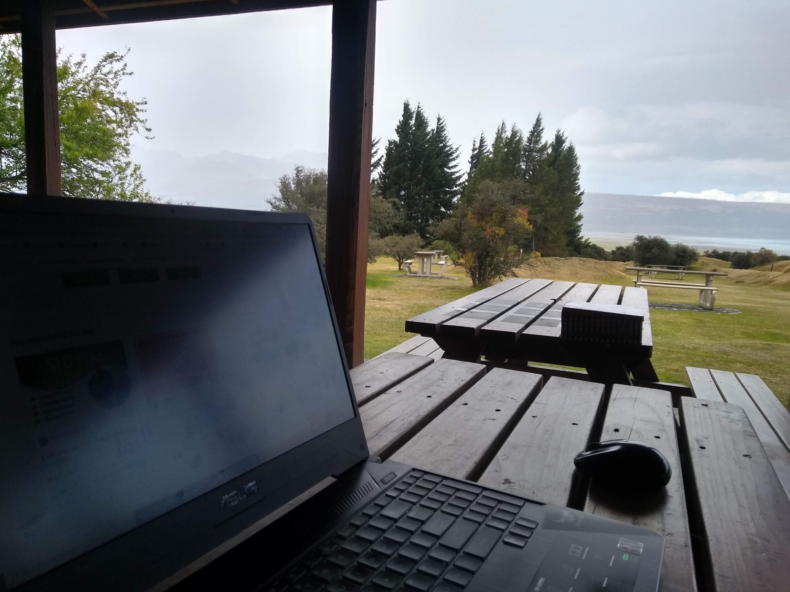 Remote Work: A laptop on a picnic table with greenery and a lake in the distance