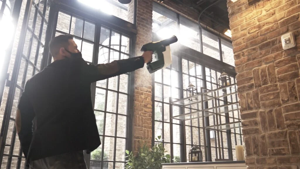 man using cleaning machine on brick wall, wearing mask