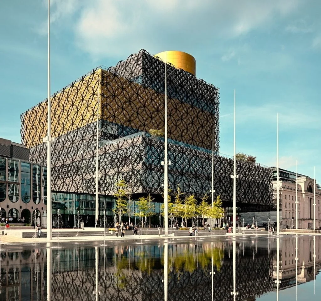 Sustainability Best Practices for Large Facilities in 2023: Large building before a water feature in a city under a blue sky