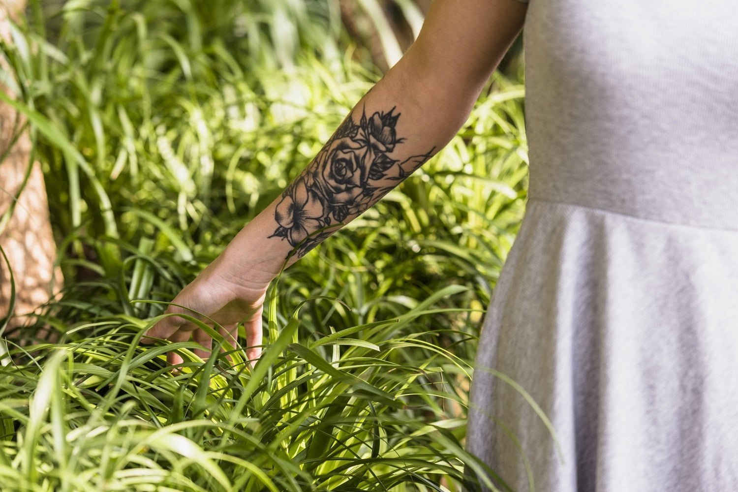 Girl touching grass in white dress witrh vegan tattoos