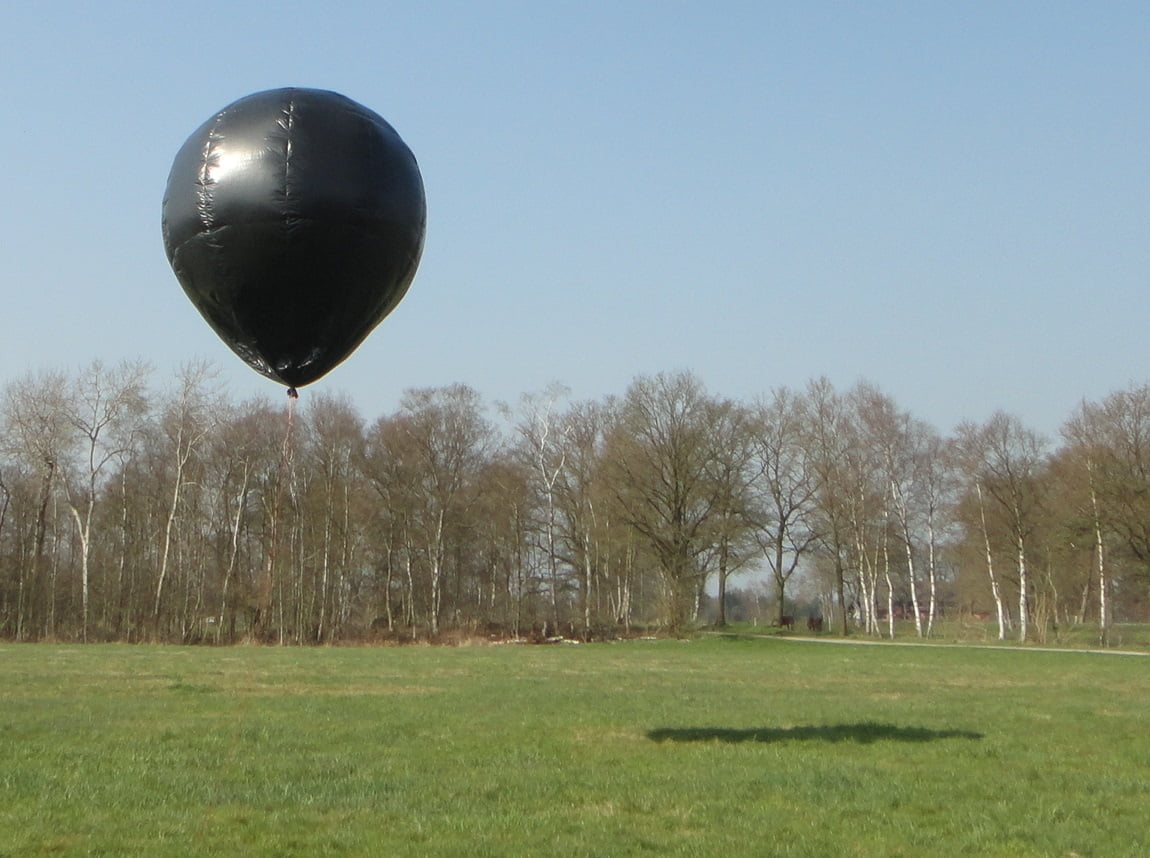 Innovations in Solar Technology: Black balloon over a green field under a blue sky