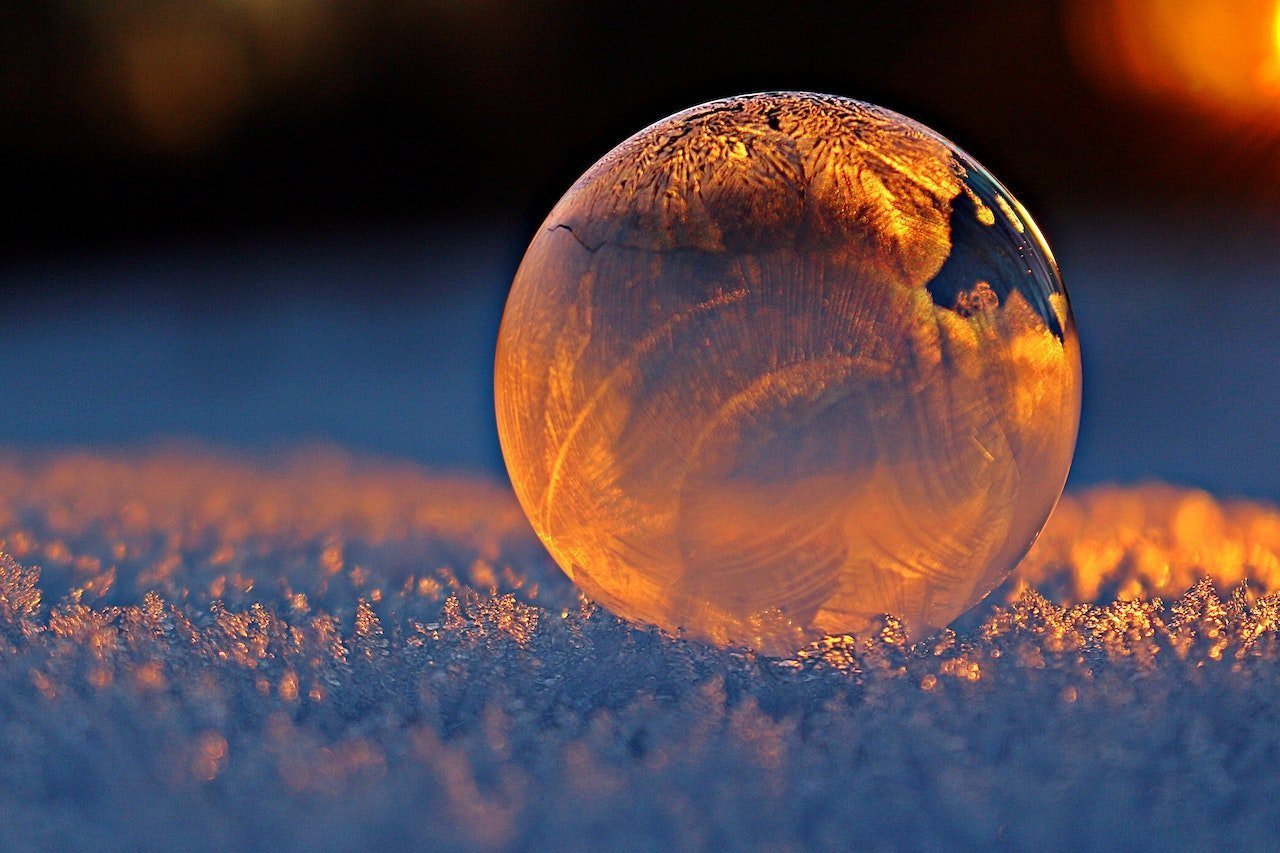 Technology, Sustainability and Society: an orange globe resting on white icy crystals like snow